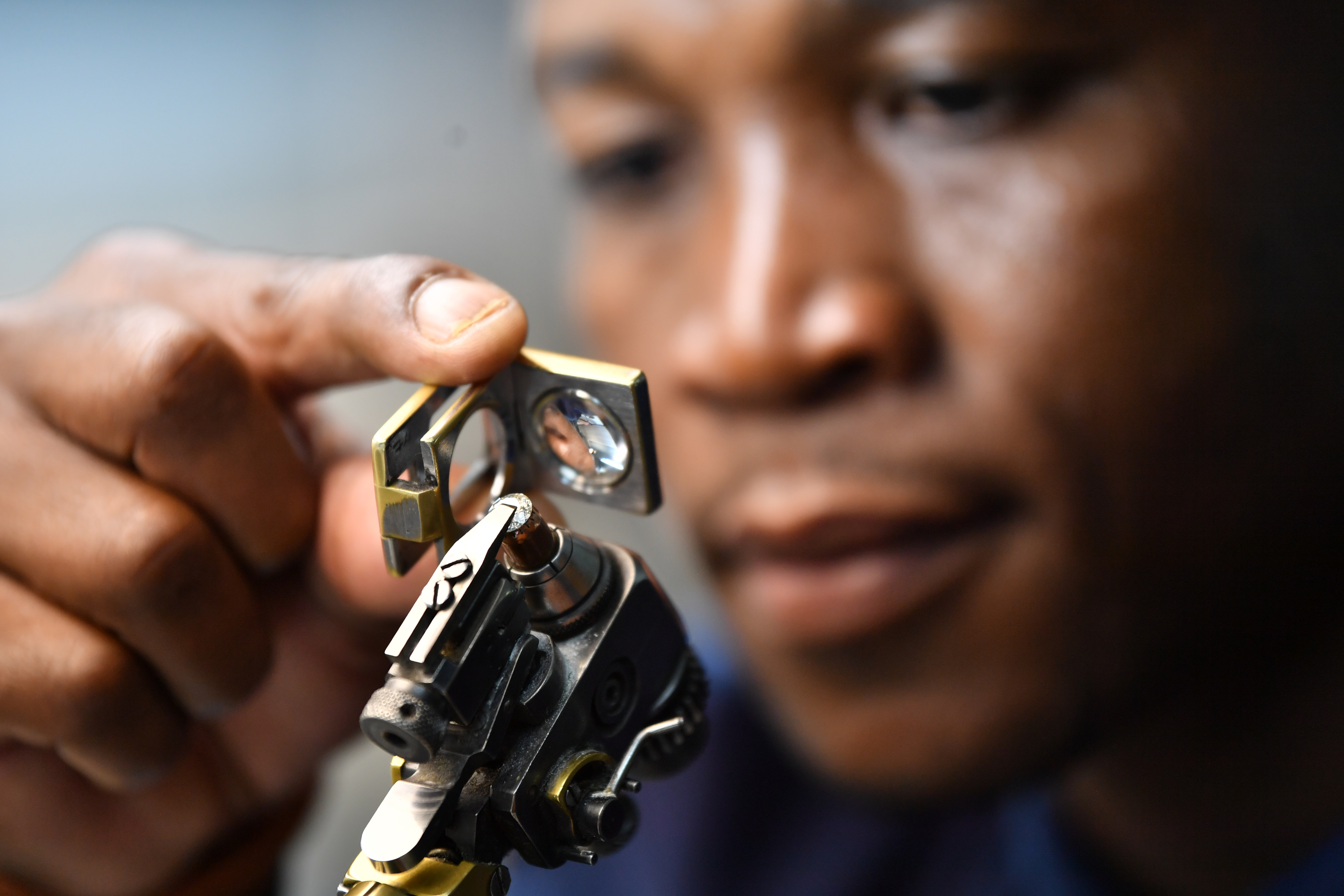 Person examining diamond with magnifying tool